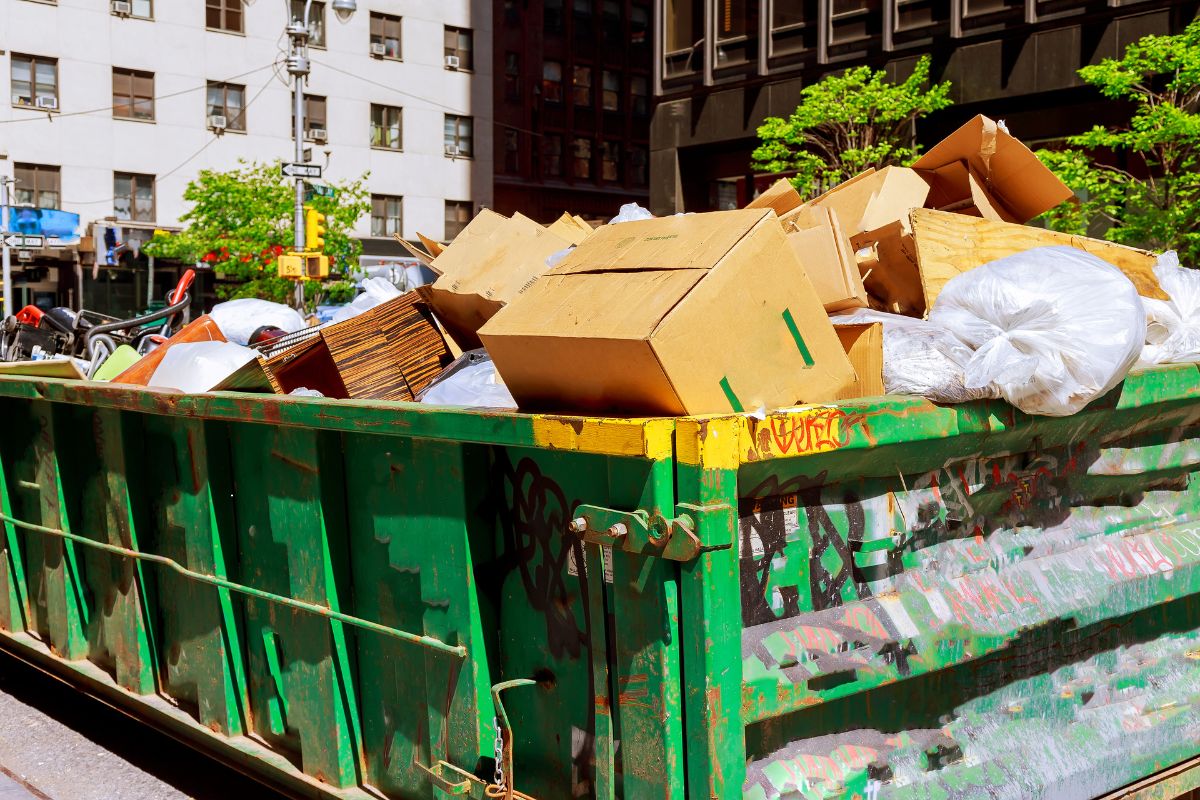 A dumpster overflowing with cardboard boxes, showcasing an outdoor junk removal service in Fresno, CA.