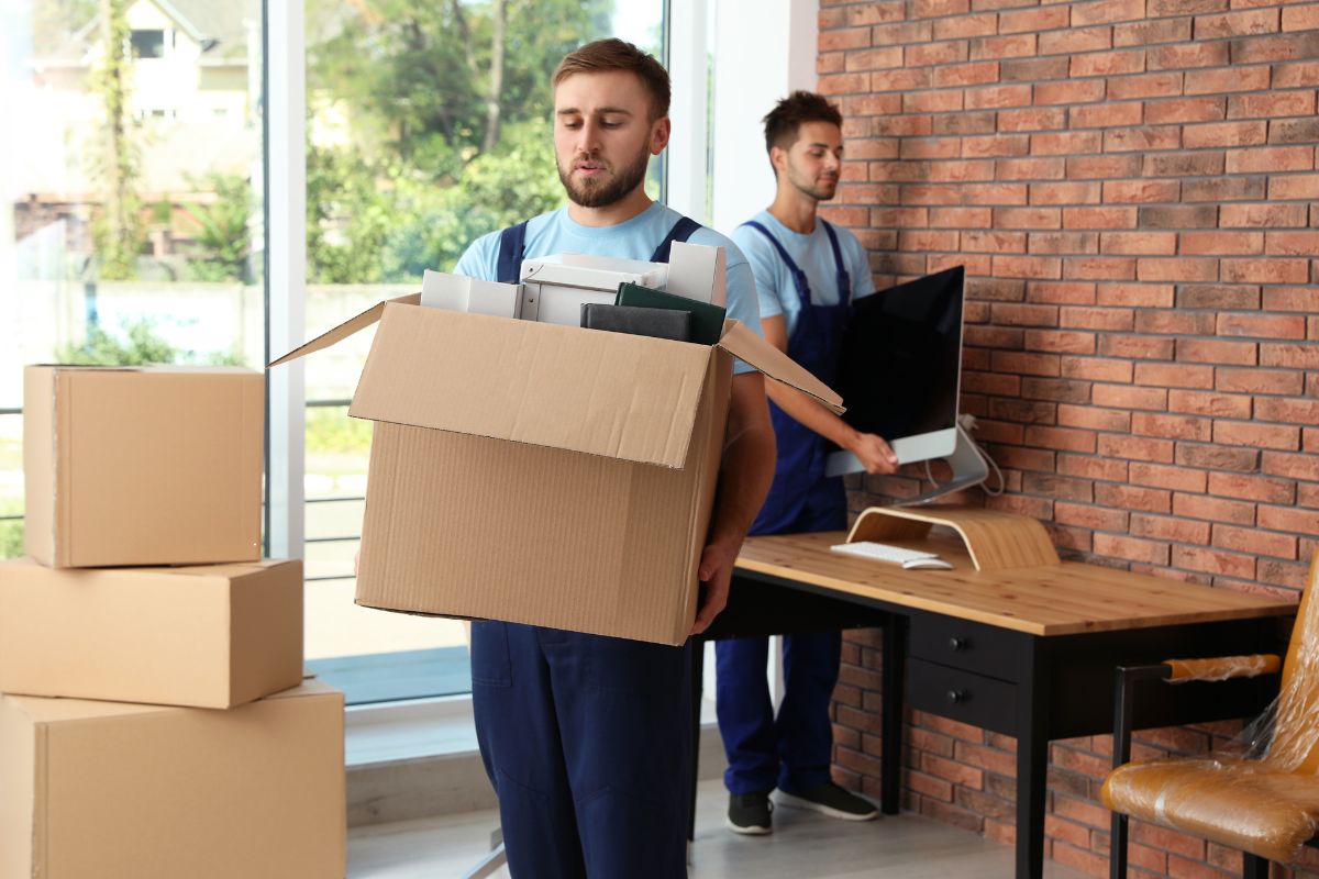 Two men moving boxes within an office as part of a clean-out service in Fresno, California.