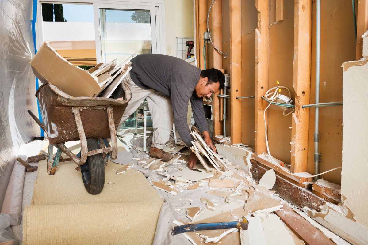 A man engaged in wall demolition inside a room, highlighting a service in Fresno, CA.