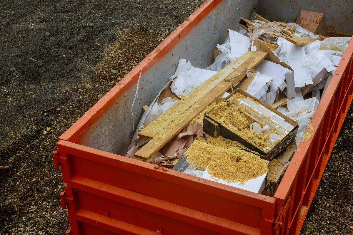 A construction dumpster packed with wood and debris, representing renovation work in Fresno, CA.